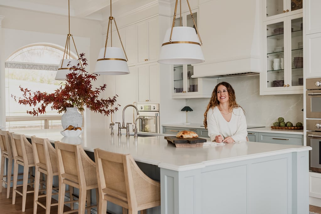 Woman in Custom 6-foot range hood feature wall with integrated Thermador appliances, coffered ceilings, and a spacious entertaining island.