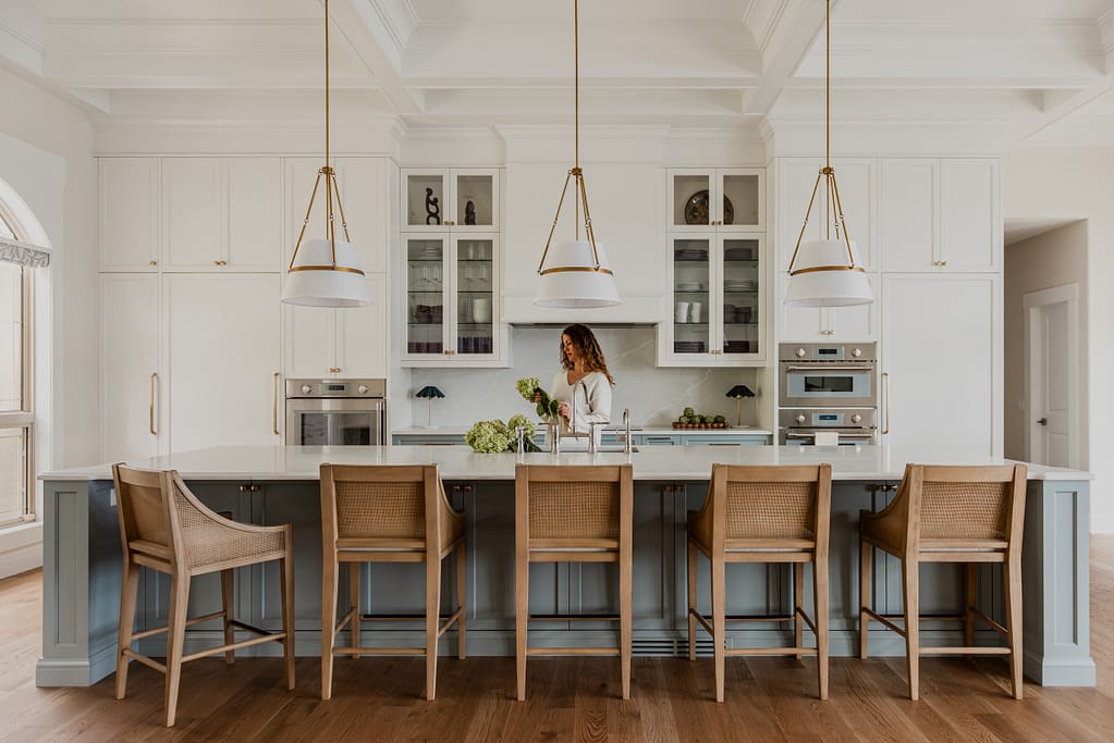 Woman in Custom 6-foot range hood feature wall with integrated Thermador appliances, coffered ceilings, and a spacious entertaining island.
