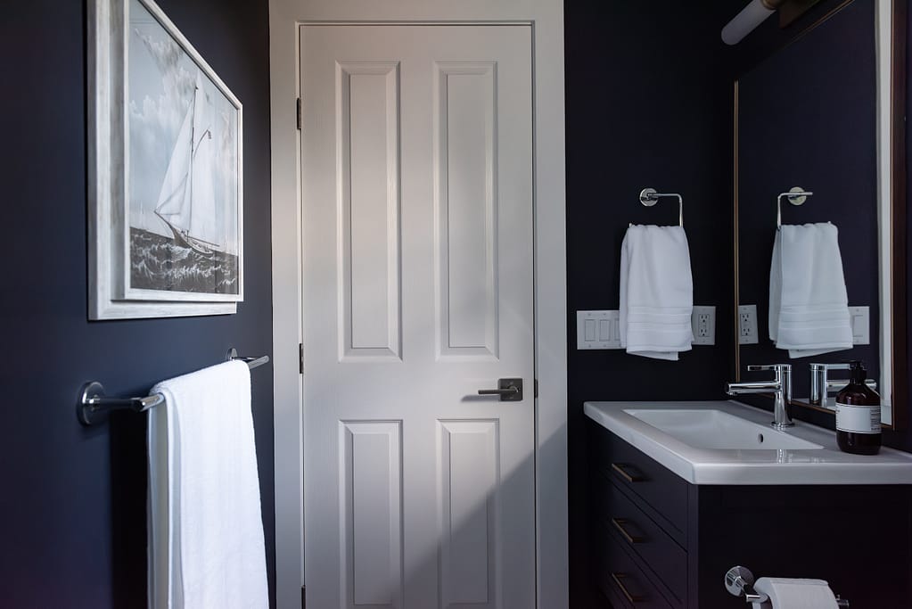 Small ensuite with colour drenched navy vanity and marble look tiled shower