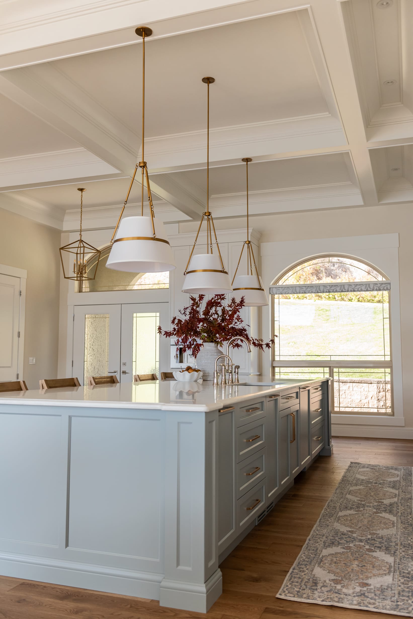 Custom 6-foot range hood feature wall with integrated Thermador appliances, coffered ceilings, polished nickel bridge faucet and a spacious entertaining island.