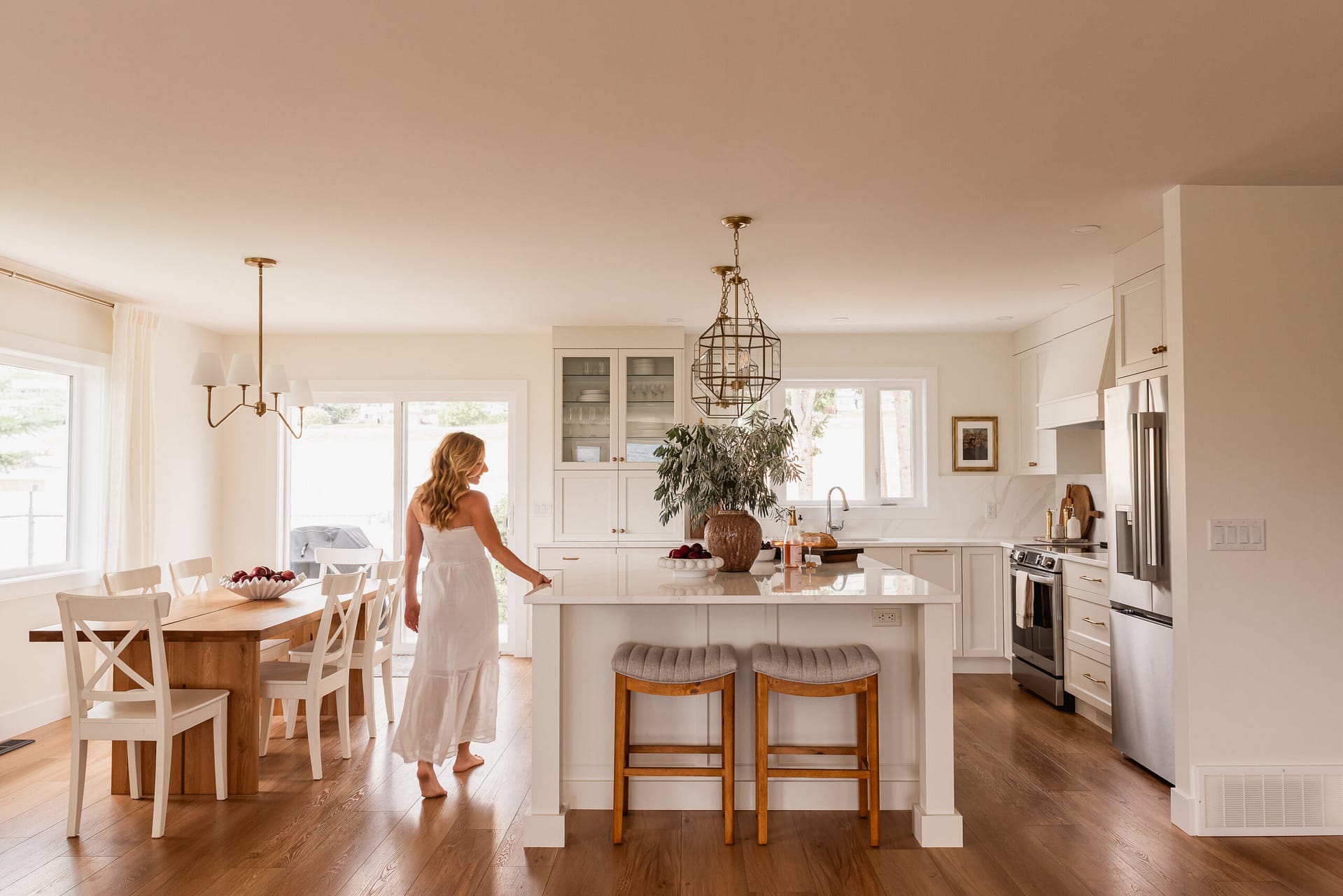 woman walking through open concept white kitchen