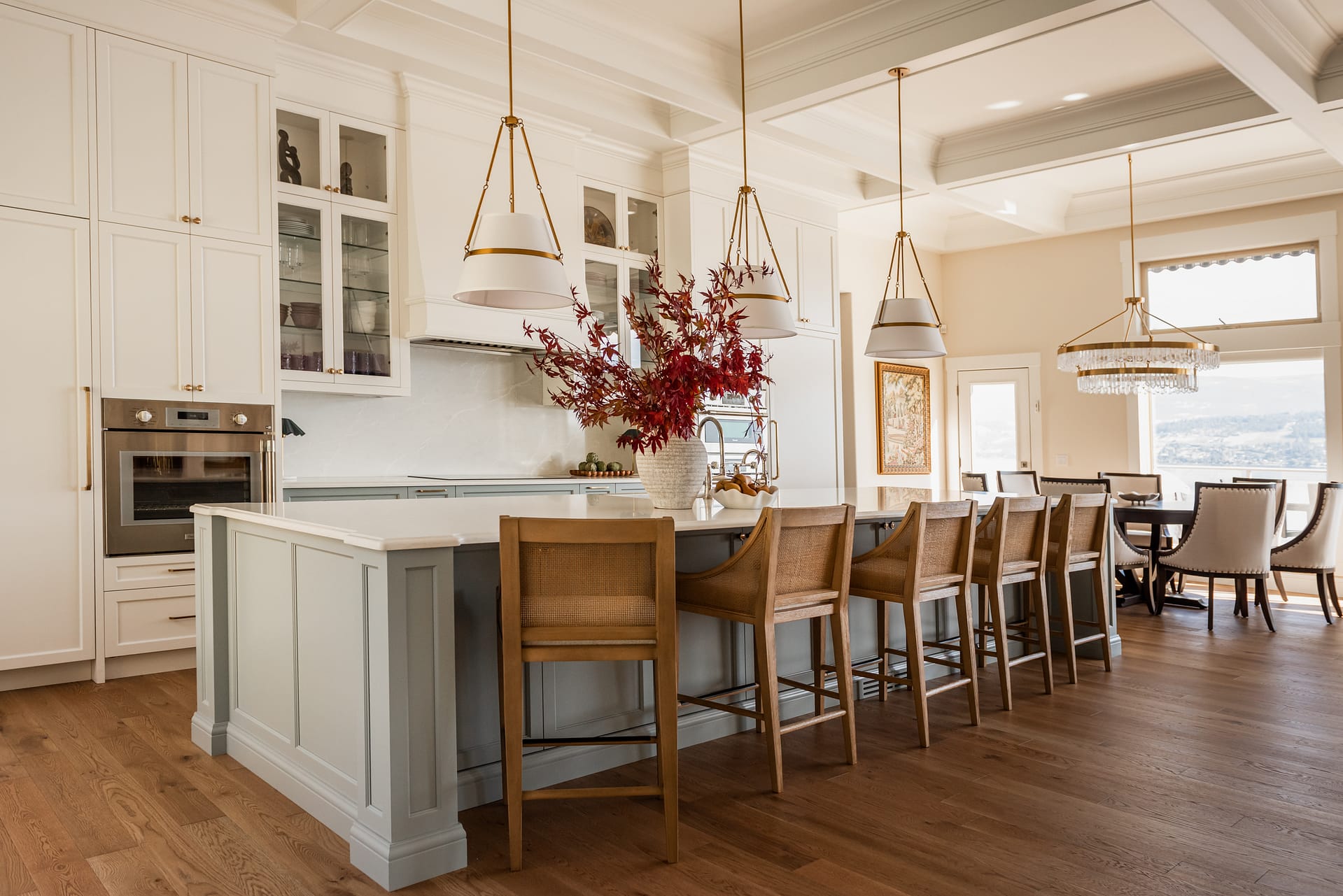 Light blue kitchen island with coffered ceiling and ogee countertop edge in a bright, transitional kitchen with tiered chandelier