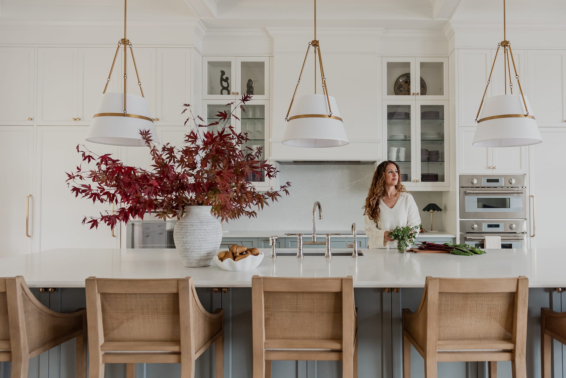 Woman in Custom 6-foot range hood feature wall with integrated Thermador appliances, coffered ceilings, and a spacious entertaining island.