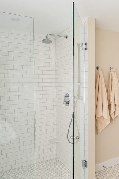 transitional walk in shower with white subway tile and warm walls