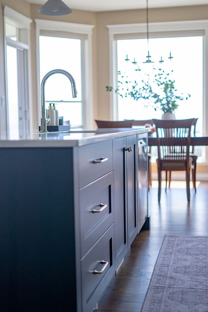 Transitional cream kitchen with navy island, modern island light