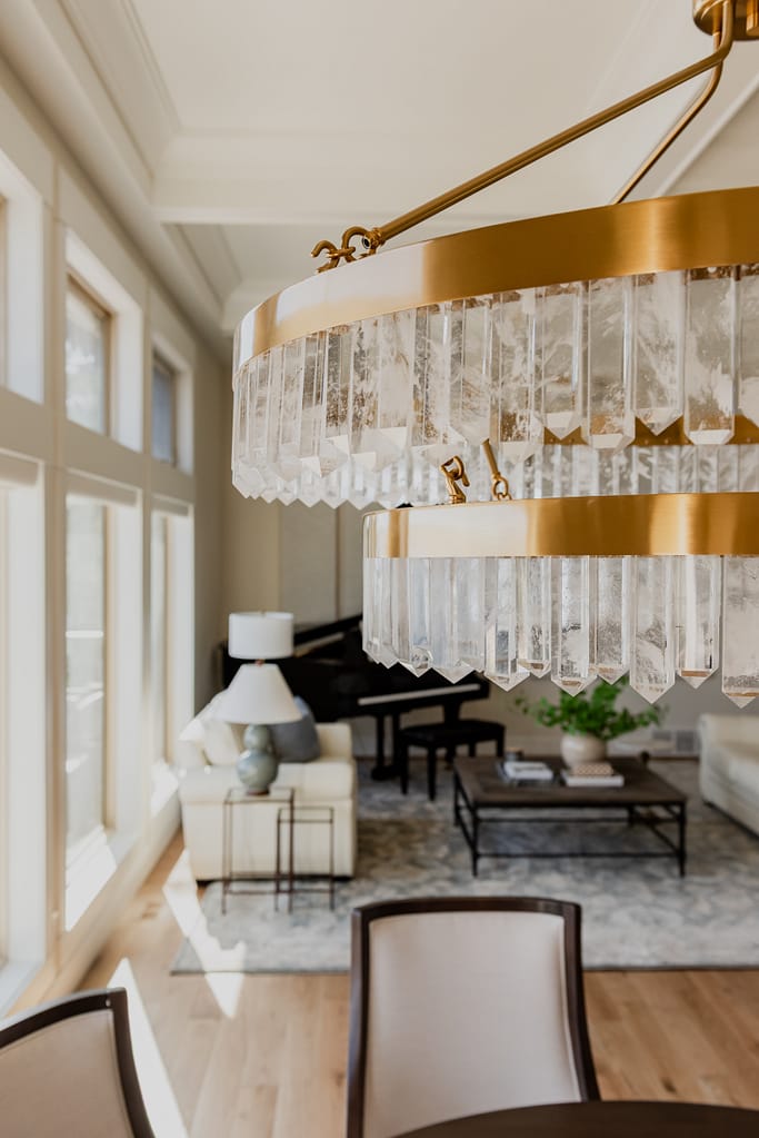Warm brass chandelier with natural calcite crystal tiers, suspended in a dining space with 12-foot ceilings.