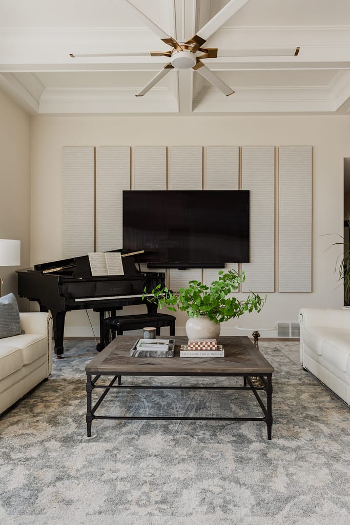 Living room with grand piano, upholstered seating, coffee table, and custom acoustic wall panels for sound control.