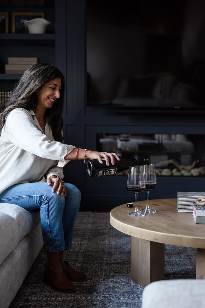 Woman pouring wine in modern living room with linear fireplace and custom built-in cabinetry