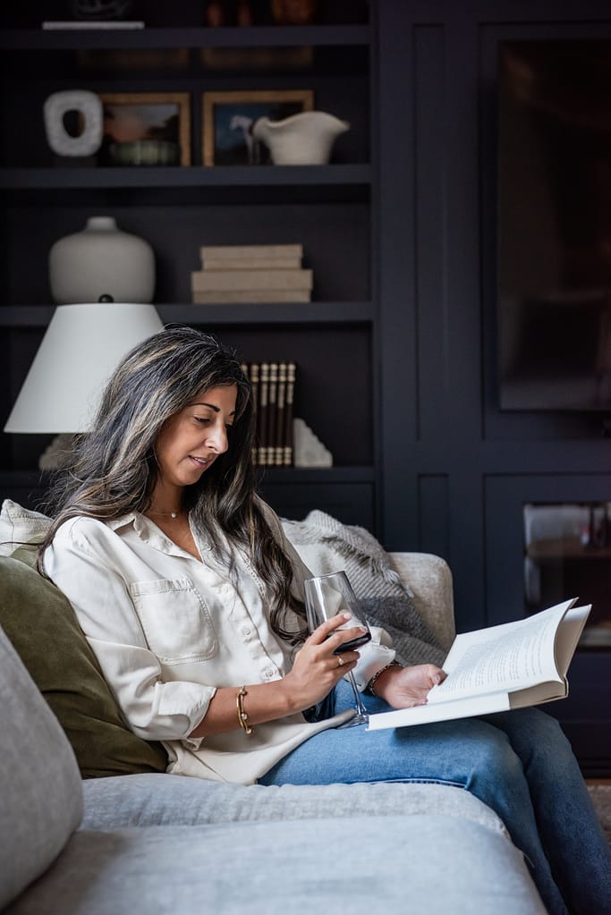 Woman decorating built in cabinetry in modern living room with linear fireplace