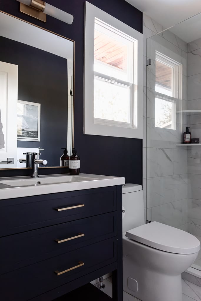 Small ensuite with colour drenched navy vanity and marble look tiled shower