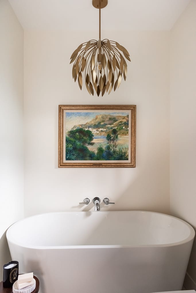 Renovated primary ensuite with deep hunter green vanity, freestanding tub, and brass lighting