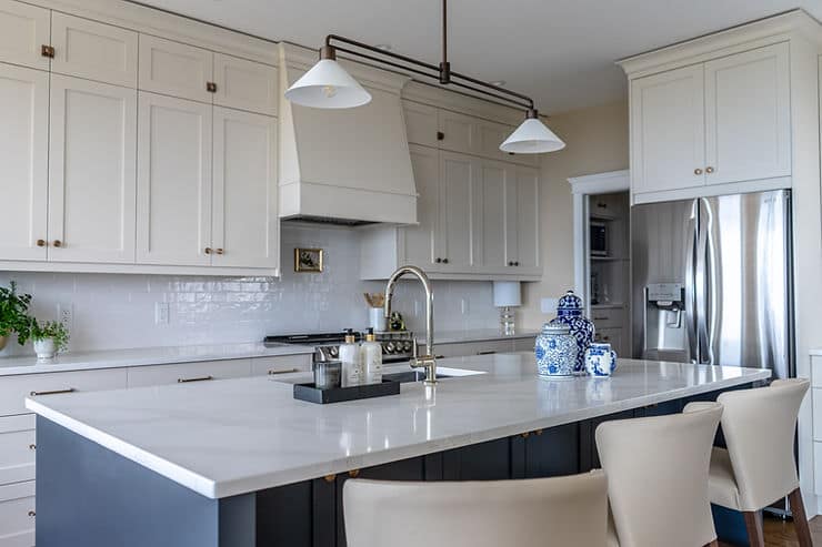 Transitional cream kitchen with navy island, modern island light