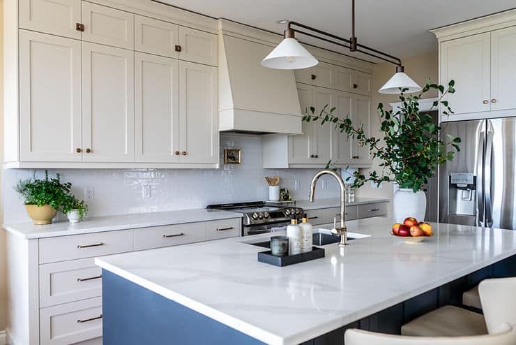 Transitional cream kitchen with navy island, modern island light