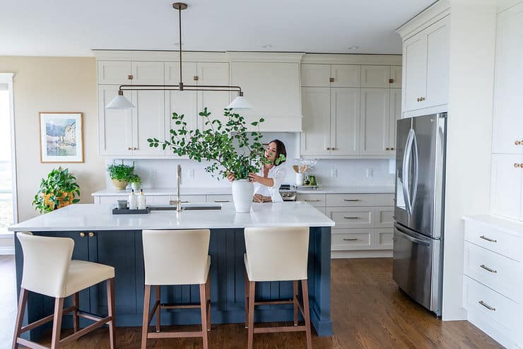 designer adjusting branches in vase on blue kitchen island
