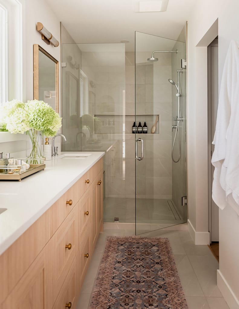contemporary ensuite wood vanity, vintage mirrors and frameless shower