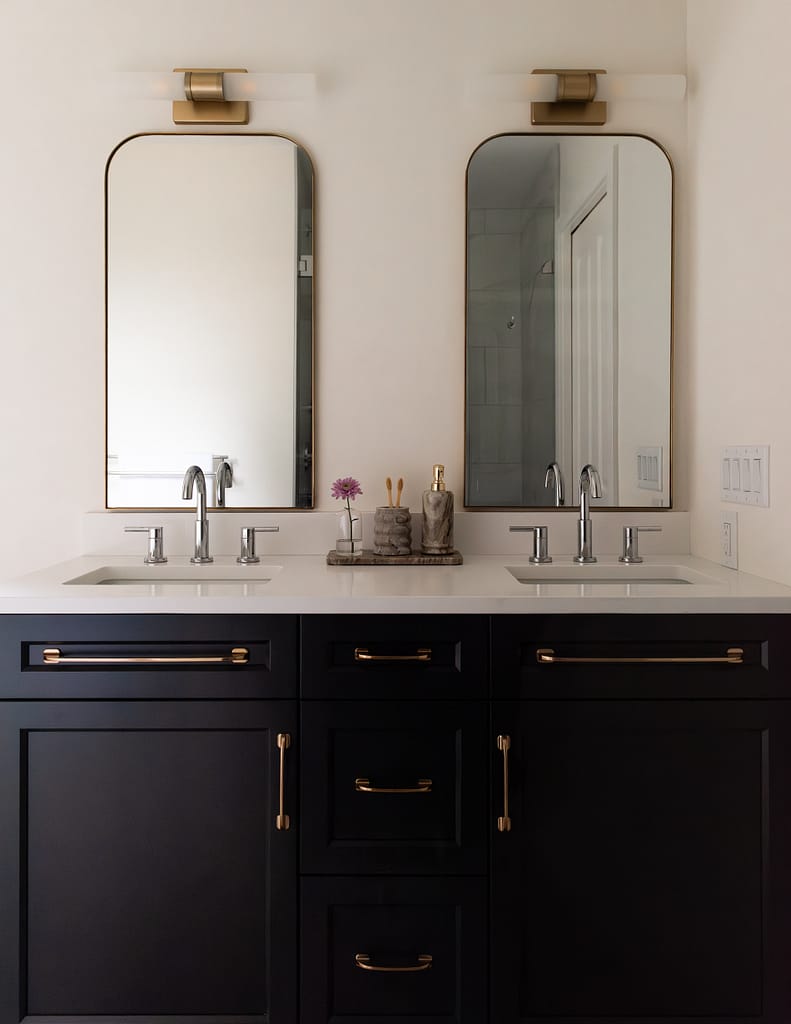 Renovated primary ensuite with deep hunter green vanity, freestanding tub, and brass lighting