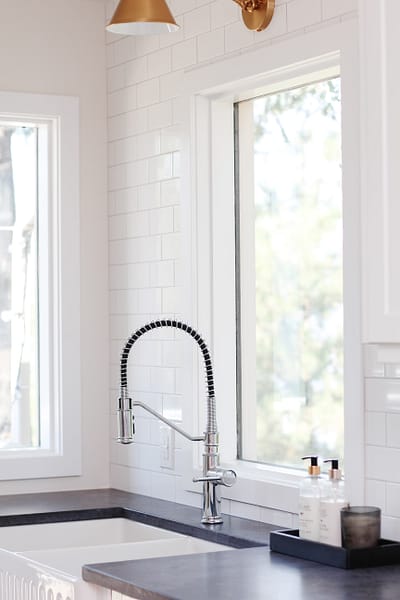 white galley kitchen with black quartz countertop, farmhouse sink, gold hardware