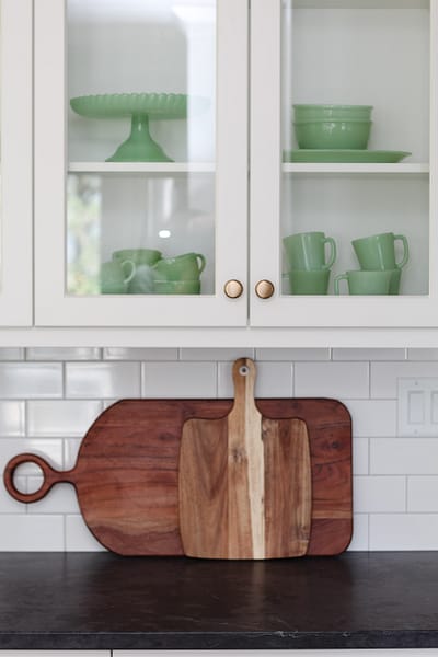 timeless white kitchen cabinets, black quartz counter, cutting boards, subway tile, glass cabinets, jadeite collection
