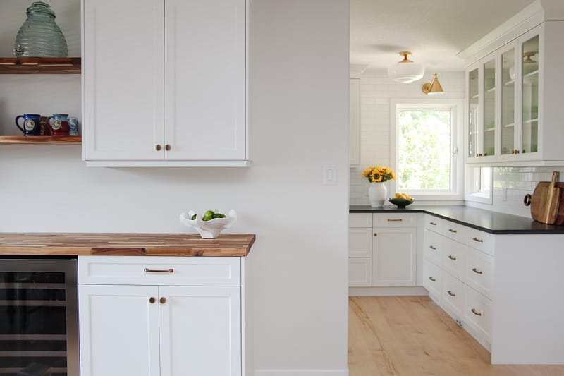 bar in dining room, white cabinets, butcher block countertop, floating wood shelves